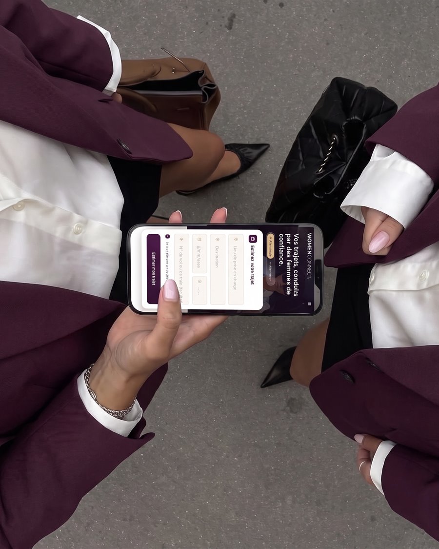 Deux femmes en blazer prune consultent le site Women Connect sur un téléphone